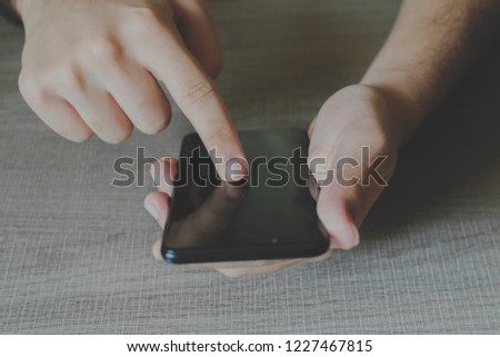 Hands holding a mobile smartphone with finger pointing to something.