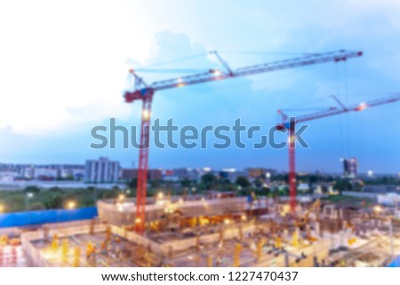 Blurred backgrounf of construction site with cranes working on a building light complex, with blue sky, sunset,twilight time of day