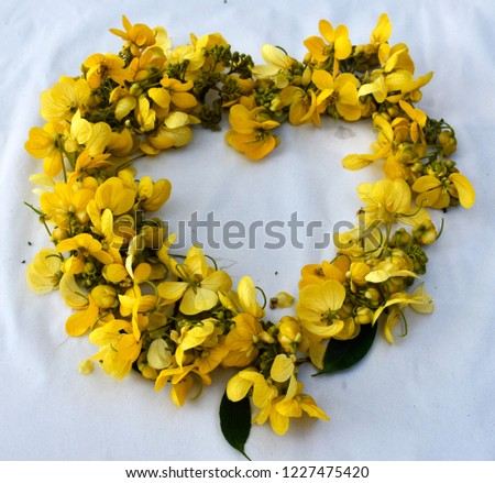 Background from heart-shaped decoration with yellow flower bouquet and green leaves.