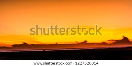 Landscape of sun over skyline in desert at White Sand Dunes Mui Ne, Vietnam. Countryside panorama under scenic colorful sky at sunset dawn sunrise. Beautiful view of bright dramatic sky & dark ground