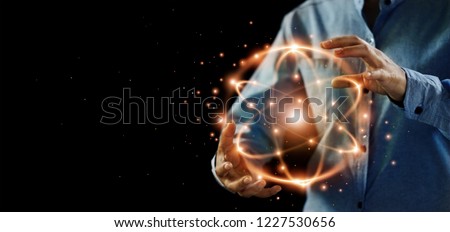 Abstract science, hands holding atomic particle, nuclear energy imagery and network connection on dark background. Royalty-Free Stock Photo #1227530656