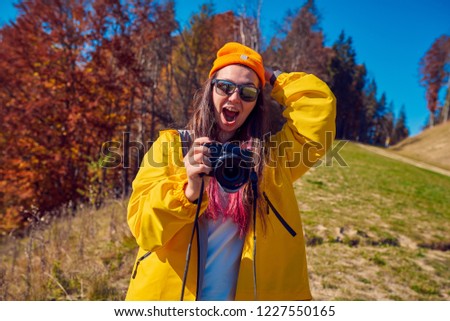Cool girl with a camera in autumn park

