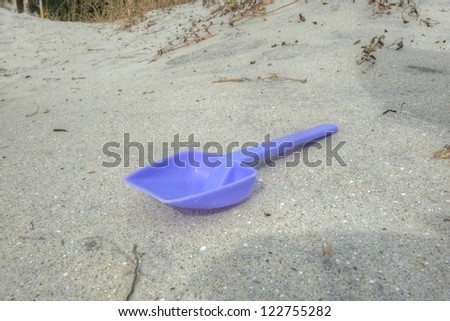 A small blue shovel on a sandy beach.