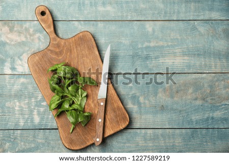 Board with fresh basil and knife on wooden background, top view. Space for text