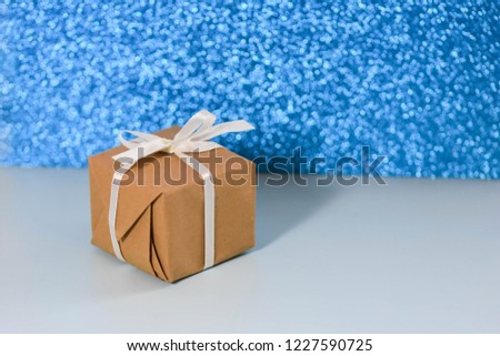Horizontal gift box kraft paper with white ribbon glitter background