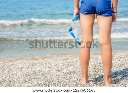 Close up young boy  holding mask and snorkel on the beach. Empty space for text.