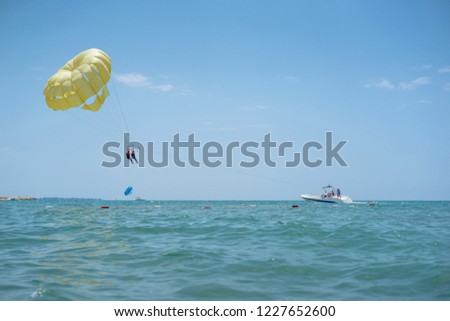 Happy couple Parasailing on Tropical Beach in summer. Couple under parachute hanging mid air. Having fun. Tropical Paradise. Positive human emotions, feelings, family, travel, vacation