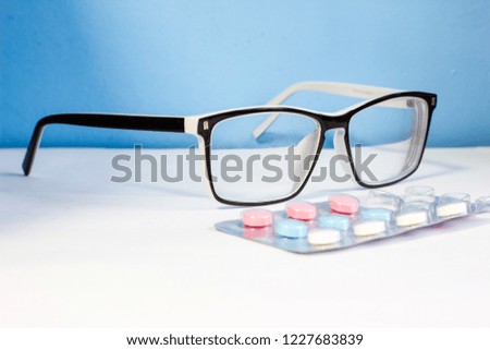 glasses and pills on blue background