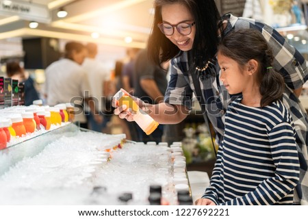Mother and daughter buying orange juice from convenience store Royalty-Free Stock Photo #1227692221