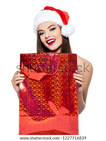 Woman in santa hat with shopping bags. Young cheerful woman with bright makeup in a santa hat, isolated on white background