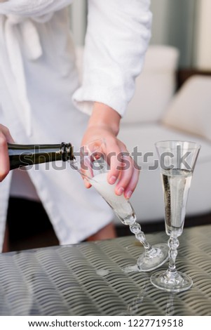 The groom pours champagne in a glass. Drink in a glass.