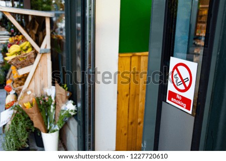 No Smoking Sign Outside Health Food Shop With Flowers In Background