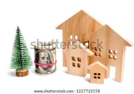 Wooden houses and Christmas tree and dollars. Christmas Sale of Real Estate. New Year discounts for buying house. Purchase apartments at a low price. Winter resort and vacation. Holiday discounts.
