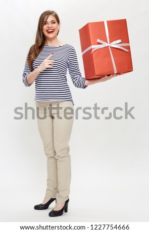 isolated full body portrait of smiling woman holding big gift box and pointing with finger.