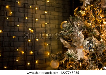 Christmas toys on a pine tree. Shiny balls, orange light bulbs. Dark background.