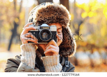 Young woman taking pictures in the autumn park. Concept girl photographer