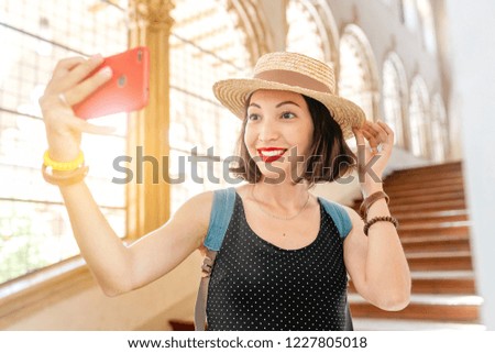 asian tourist woman visiting Europe and making selfie with her smartphone inside some travel attraction site