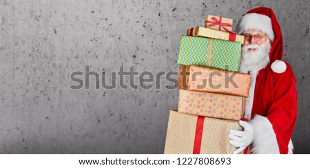 Santa Claus holding a stack of Christmas presents against a plain background with copy space.