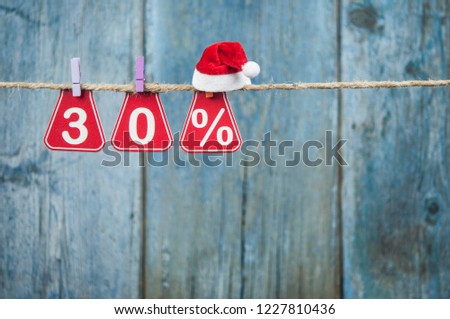 Sale tags with sign percent hanging from brown rope over wooden wall. Happy New Year sale concept