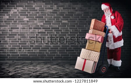 Santa Claus with presents on delivery trolley in an industrial postal theme with a dark background and copy space.