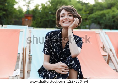 Happy young woman resting at the park, looking at camera