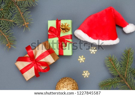 Christmas decoration. Gift boxes, Santa's hat, toy ball, decorative snowflakes and natural fir tree branches on gray background. Top view. Christmas greeting card concept.