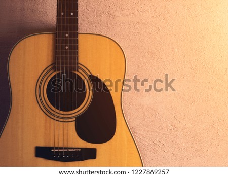 old acoustic guitar on a sandy texture. sunlight.