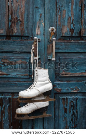 Pair of vintage white Ice Skates hanging on the blue rustic door, toned