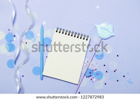 Empty note pad on blue frozen festive background with confetti and sparkles. Bright and festive. Mock up for New Year or Christmas greeting or goals.