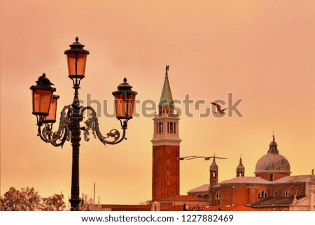 Venice sunset, famous column with winged lion, street lamp and San Giorgio Maggiore church at dusk in Venice, Italy, warm toned