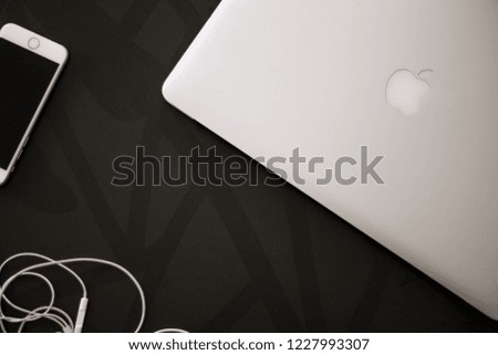 Macbook, iPhone and earphones viewed from the top on a black table