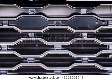 Close up of luxury sports car front grill. Grid of car radiator metal grill pattern. Garage, car detailing, mechanic shop wallpaper and background.