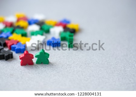 Groups of colorful meeples isolated on gray background. Blue, red, black, green and yellow. Small figures of man. Board games concept. Couple of leaders of community. Business strategy.