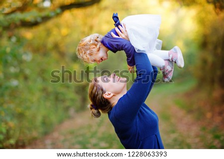 Happy young mother having fun cute toddler daughter, family portrait together. Woman with beautiful baby girl in nature and forest. Mum with little child outdoors, hugging. Love, bonding.