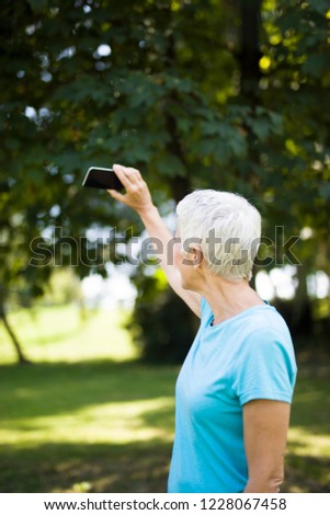 Sporty senior woman taking selfie in the park after workaout