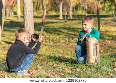 Two friends, brothers are photographed on the phone in the park on a sunny day