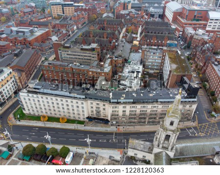 Aerial photo overlooking Leeds City Center in West Yorkshire showing buildings, businesses, hotels, pubs and roads and paths, taken on a cloudy day.