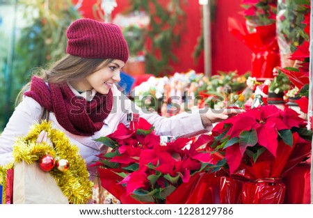 Pretty young girl buying floral compositions at the Christmas fair 