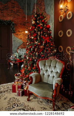 Christmas interior of the living room with red and gold colors. Room with a large Christmas tree, decorated with beautiful garlands, toys and decor. Under the tree are Packed gifts.