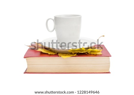 Cup of coffee with autumn leaves on book. Isolated on white.