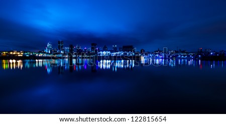 Wide Panoramic View of Montreal, with reflection light in the water, in blue tone at night.