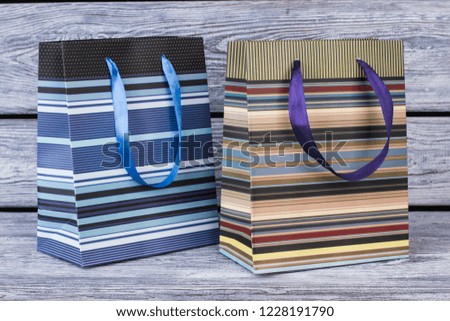 Two striped shopping bags on wooden background. Two paper bags with colorful stripes, horizontal image.