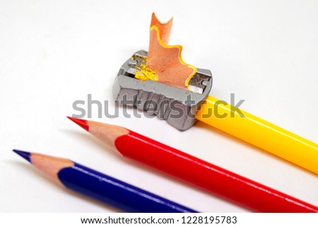 Color pencil and prism sharpener macro photo on white background. Sharpening pencils concept. Drawing as hobby banner template. Yellow, red and blue crayons closeup. Children art class creative hobby