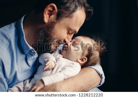 Closeup portrait of middle age bearded Caucasian father hugging and kissing newborn baby. Man parent holding child. Authentic lifestyle real life touching tender moment. Single dad family life Royalty-Free Stock Photo #1228212220