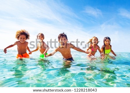Kids laughing and playing in water at the seaside Royalty-Free Stock Photo #1228218043