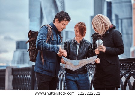 Group of tourists searching place on the map in front of skyscrapers