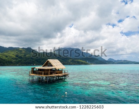 Over water bungalow of black pearl farmers. Blue azure turquoise lagoon with corals. Emerald Raiatea island, Leeward / Society islands, French Polynesia, Oceania, South Pacific Ocean near Tahiti. Royalty-Free Stock Photo #1228225603