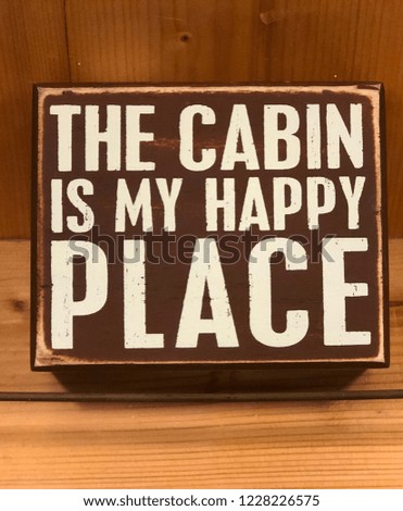 The cabin is my happy place - cute decorative sign on display in a wood background