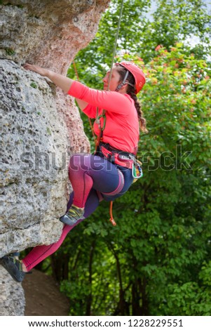 Photo of athlete girl in helmet clambering over rock