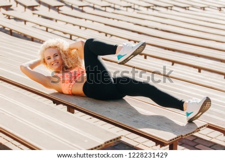 Picture of sports woman exercising among benches in summer day